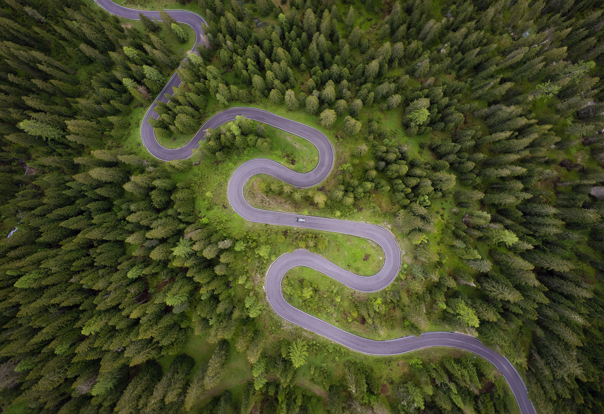 Perspectiva cenital aérea de una carretera serpenteante a través de un bosque. Clave para la composición en fotografía de drones.