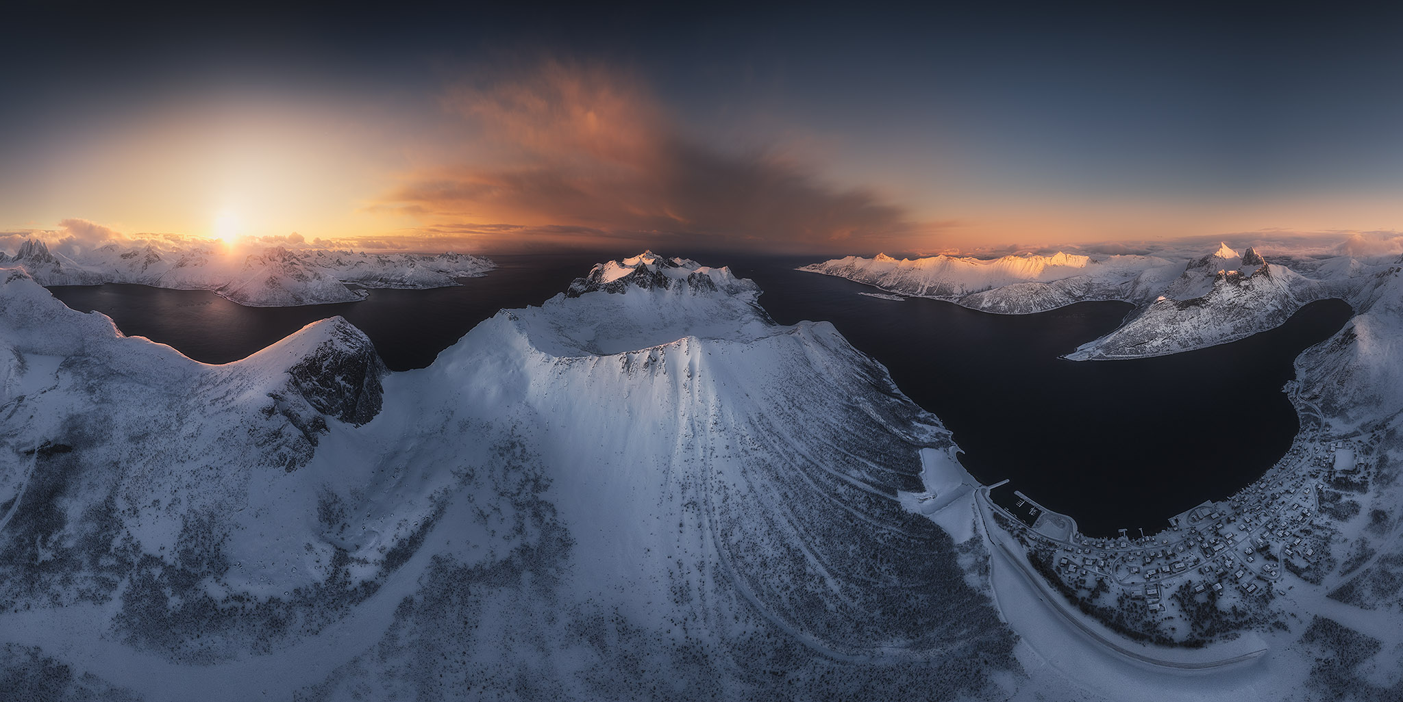 Taller de fotografía con drones: Vista aérea de picos nevados y fiordos noruegos al amanecer.